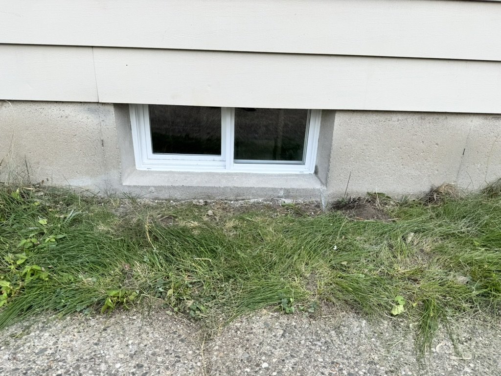 New white vinyl basement window after replacement, West Michigan